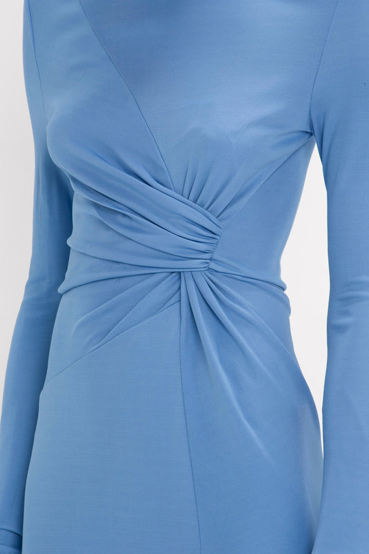 Close-up of a Victoria Beckham High Neck Asymmetric Draped Dress in Oxford Blue with long sleeves and a twisted fabric detail at the waist.