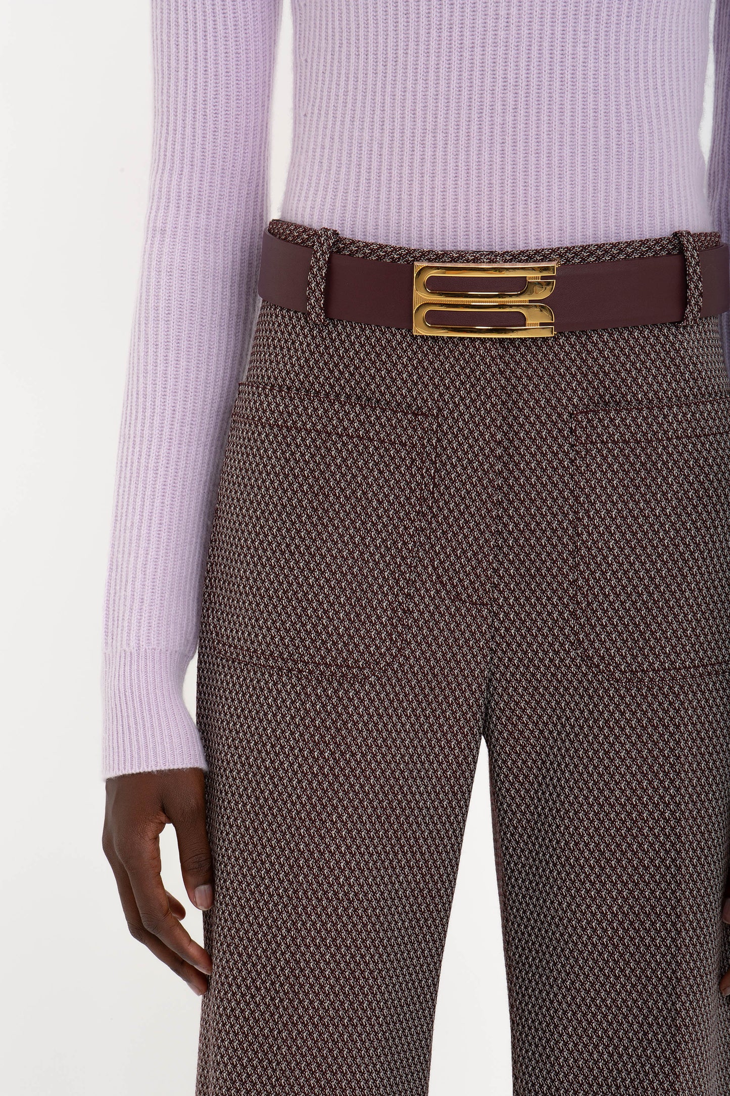 A person wearing a Victoria Beckham Double Collared Jumper In Petunia and patterned pants with a thick belt featuring a gold buckle.