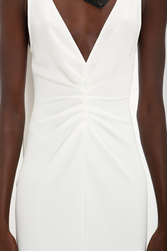 Close-up of a person wearing an elegant midi dress, an Exclusive V-Neck Gathered Waist Floor-Length Gown In Ivory by Victoria Beckham, accentuating their hourglass silhouette.