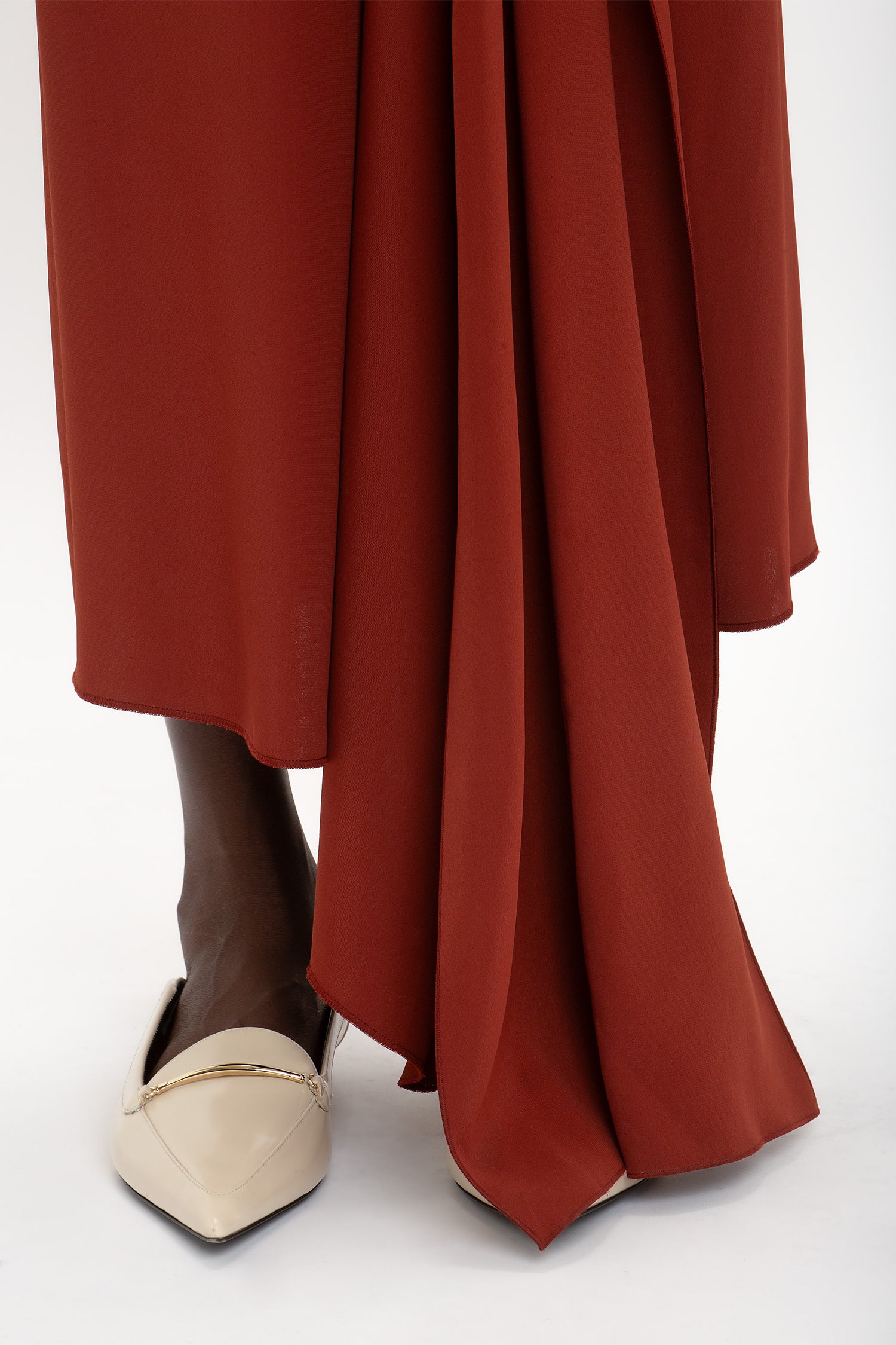 Close-up of a person wearing a High Neck Tie Detail Dress In Russet by Victoria Beckham and pointed beige shoes.