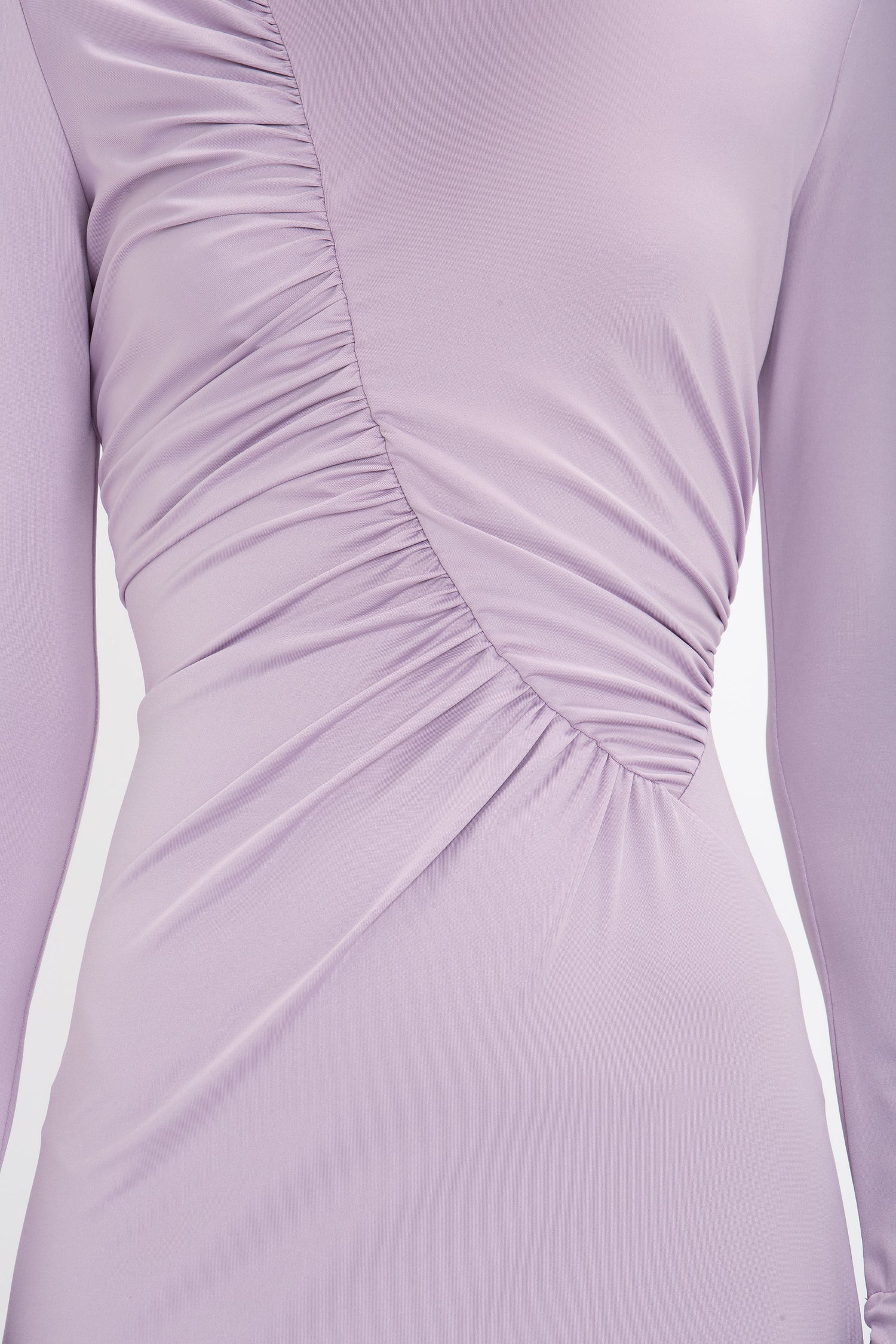 Close-up of a lavender-colored Victoria Beckham Ruched Detail Floor-Length Gown In Petunia with asymmetric ruching on the front. The figure-flattering stretch jersey fabric appears smooth and slightly shiny, exuding an understated glamour.