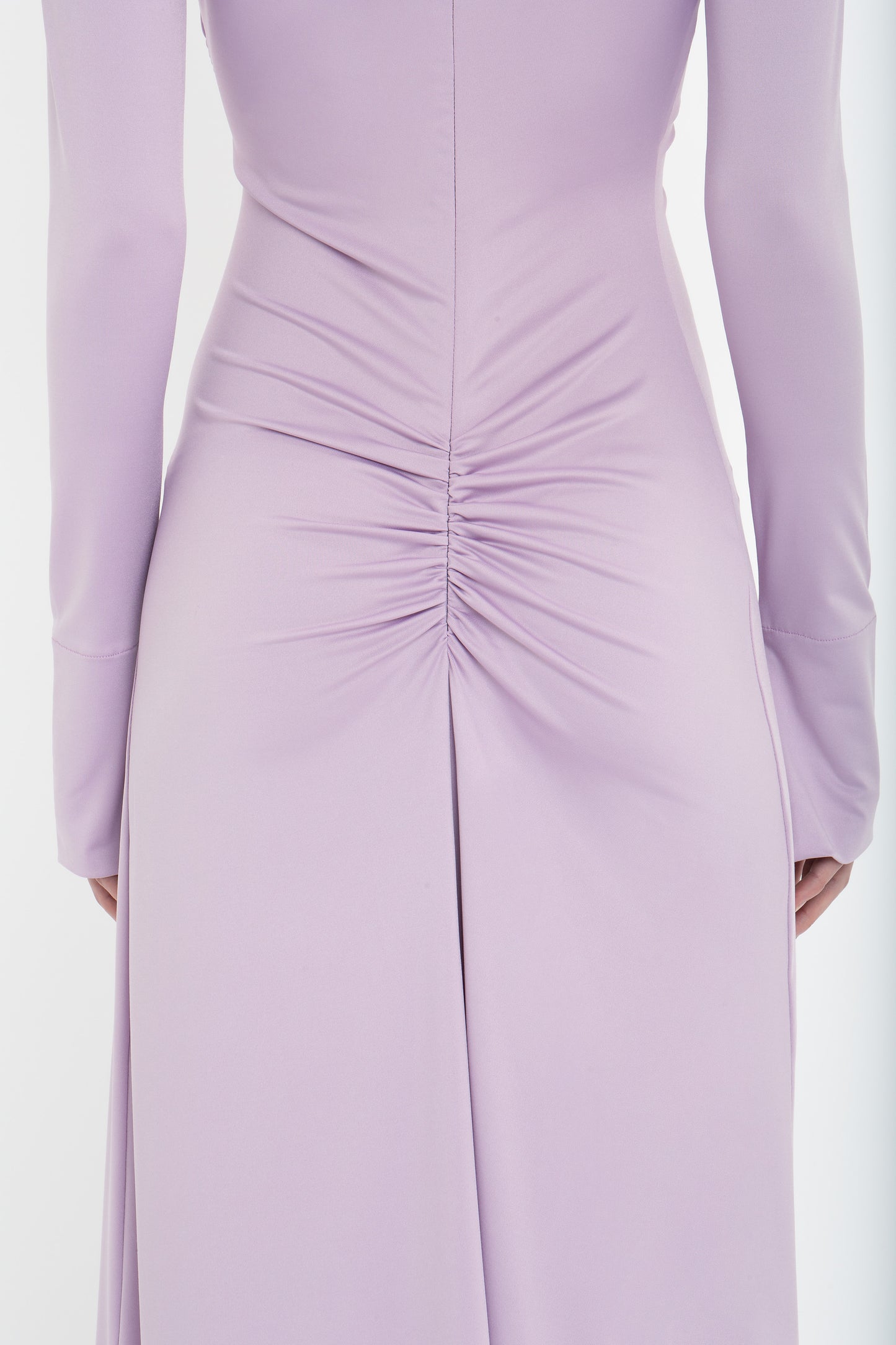 Close-up of the back of a Victoria Beckham Ruched Detail Floor-Length Gown In Petunia with long sleeves, featuring a gathered ruched detail at the lower back and a flowing skirt, exuding understated glamour.