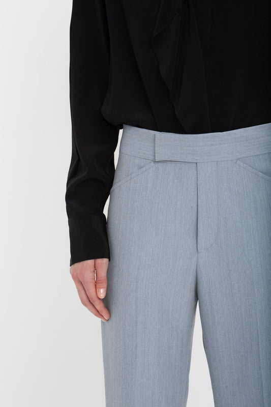 A person wearing a black long-sleeve shirt tucked into light gray, 1970s-inspired Exclusive Wide Cropped Flare Trouser In Marina by Victoria Beckham.