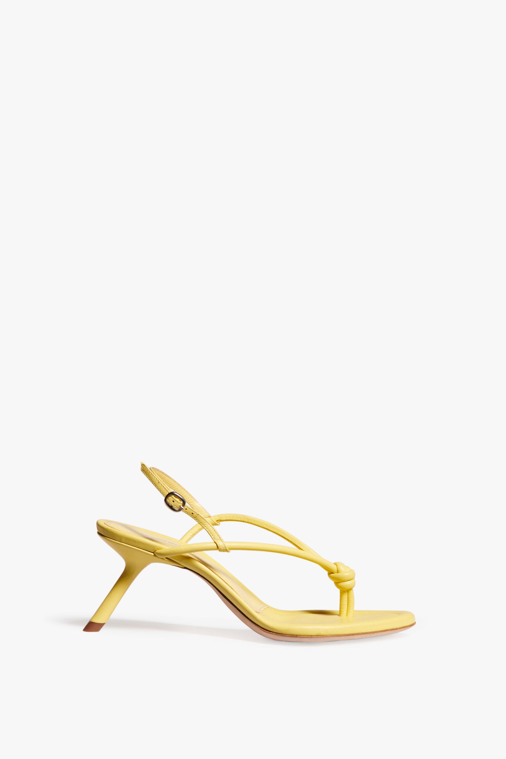 A pale yellow nappa leather high-heeled sandal with a thong design, tubular straps, and an ankle strap buckle closure on a white background by Victoria Beckham called Estelle in Pale Yellow.