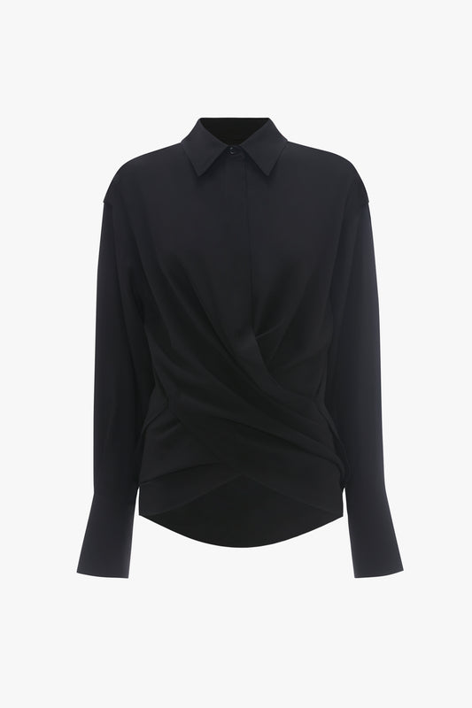 A black long-sleeve silk Wrap Front Blouse In Black with an asymmetric twisted front design, displayed on a plain white background by Victoria Beckham.