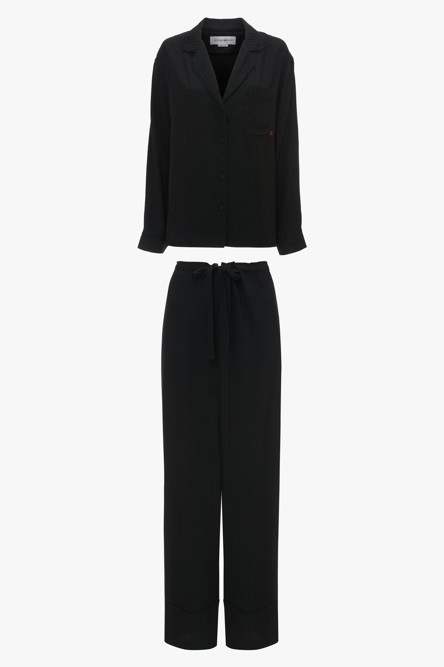 A Victoria Beckham VB Monogram Pyjama Sleep Set In Black consisting of a long-sleeve button-up shirt with a chest pocket and matching trousers with a drawstring waist, ideal for loungewear. Displayed on a white background.