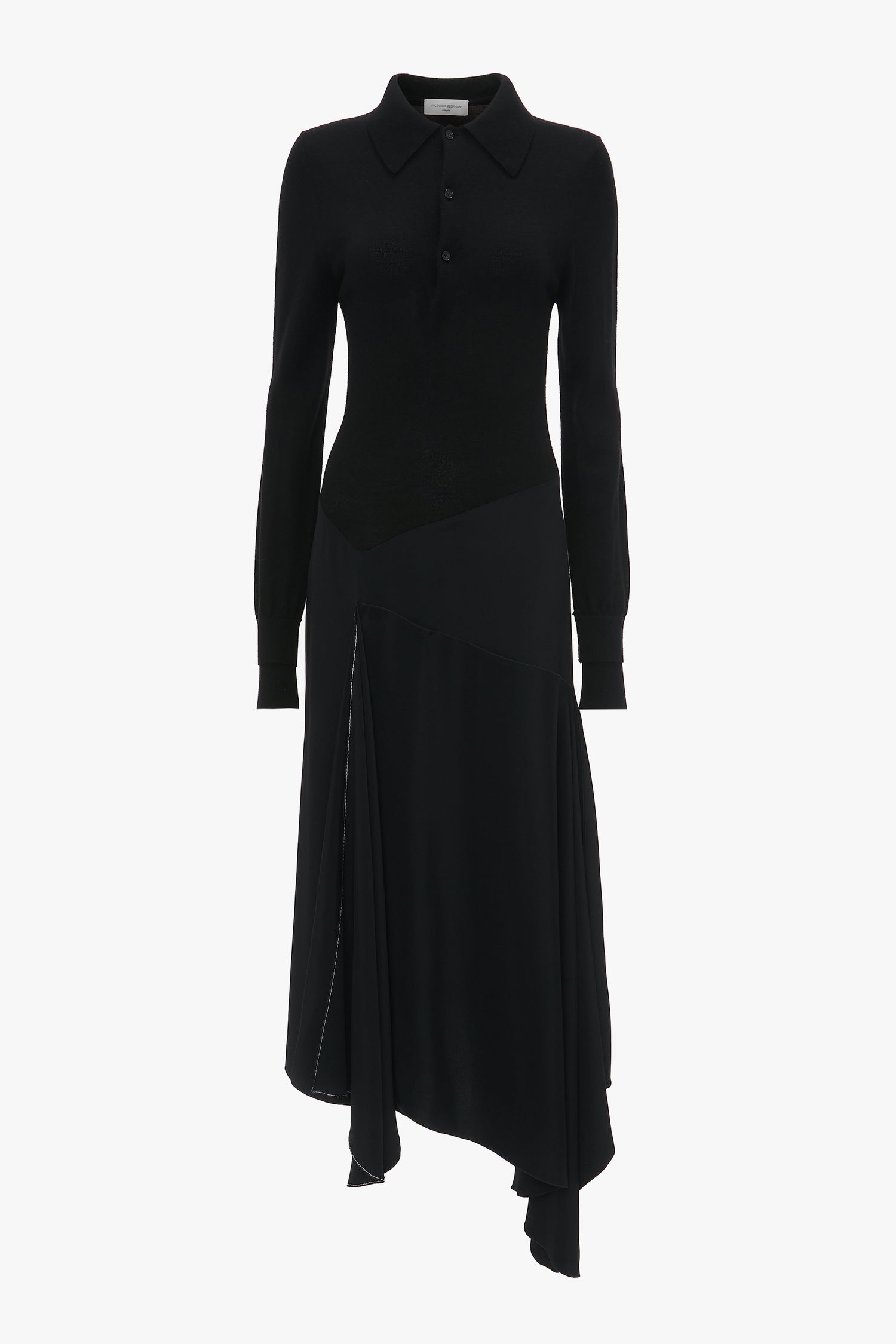 A long-sleeve Henley Shirt Dress In Black with a collared neckline and asymmetrical hem. The dress, made from luxurious merino wool knit, features button details on the upper section and an elegant asymmetric waist seam. This piece is by Victoria Beckham.