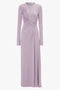 A long-sleeved, lavender Ruched Detail Floor-Length Gown In Petunia by Victoria Beckham crafted from stretch jersey, featuring asymmetrical ruching across the bodice and a slit at the hem for an understated glamour.