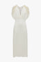 A sleeveless, knee-length Exclusive V-Neck Ruffle Midi Dress In Ivory by Victoria Beckham, featuring a fluid crepe back satin fabric, with ruched detailing on the shoulders.