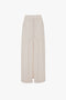 A long beige "Deconstructed Floor-Length Skirt In Bone" by Victoria Beckham with a high waist, visible stitching, two side pockets, and a front slit, displayed on a plain white background.