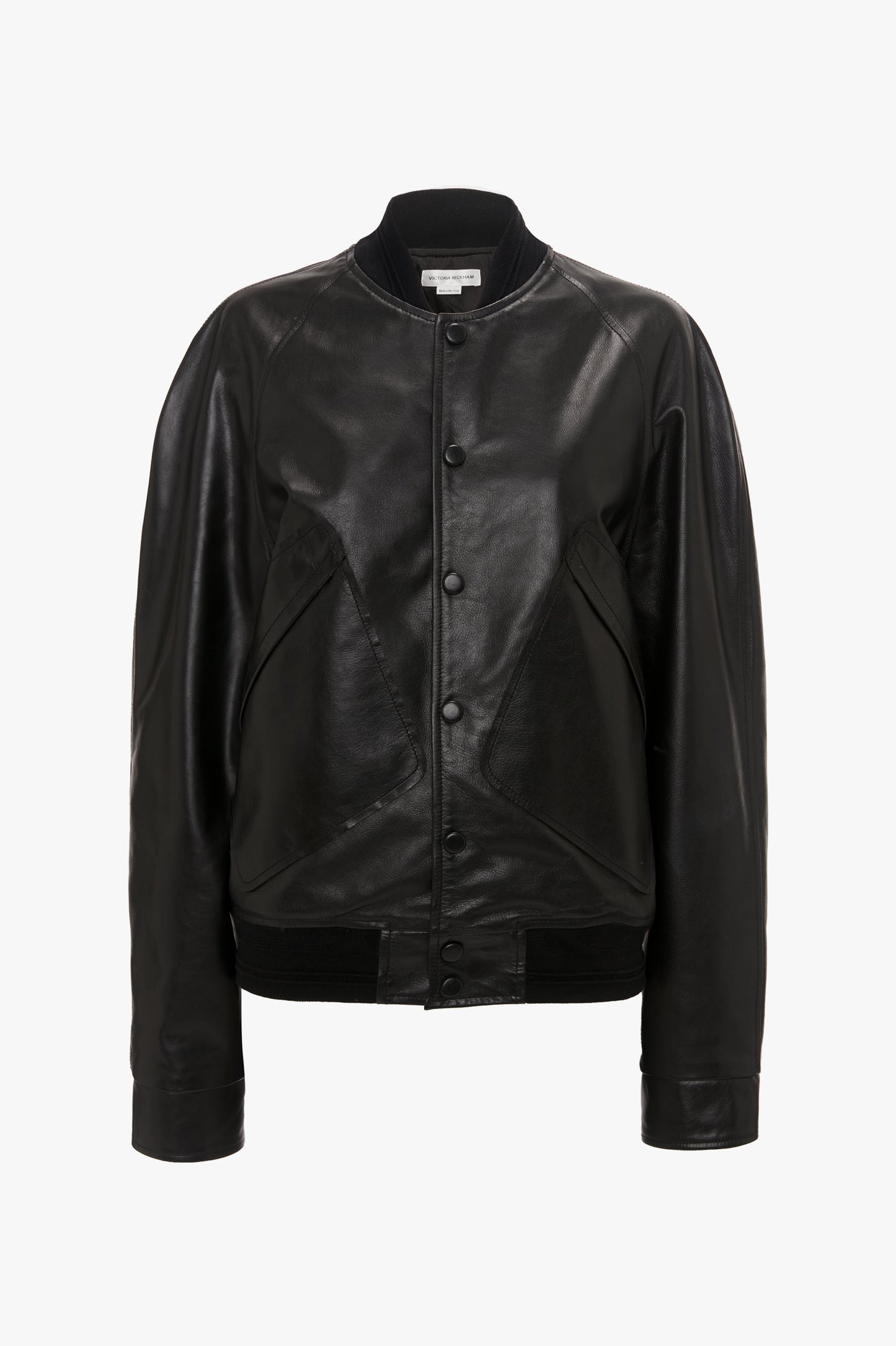 The Leather Varsity Jacket In Black by Victoria Beckham is a collegiate-style black leather varsity jacket featuring front button closure and ribbed cuffs, crafted from premium calf leather, set against a white background.