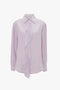 A light purple silk Asymmetric Ruffle Blouse In Petunia by Victoria Beckham, with a ruffled front and a classic collar, displayed on a white background.