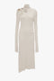 Long-sleeved, knee-length cream Long Sleeve Cut-Out Jersey Midi Dress In Bone by Victoria Beckham in liquid crepe jersey with asymmetric cutouts and high neckline, featuring decorative stitching on the front.