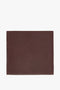 A brown supple Foulard In Bordeaux leather placemat with a simple stitched border, displayed on a plain background by Victoria Beckham.