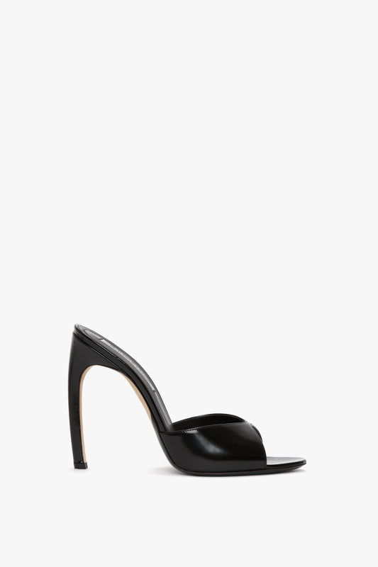 A Victoria Beckham Classic Mule In Black Calf Leather with an open-toe design and a seductive curved stiletto heel, crafted from luxury calf leather, set against a white background.