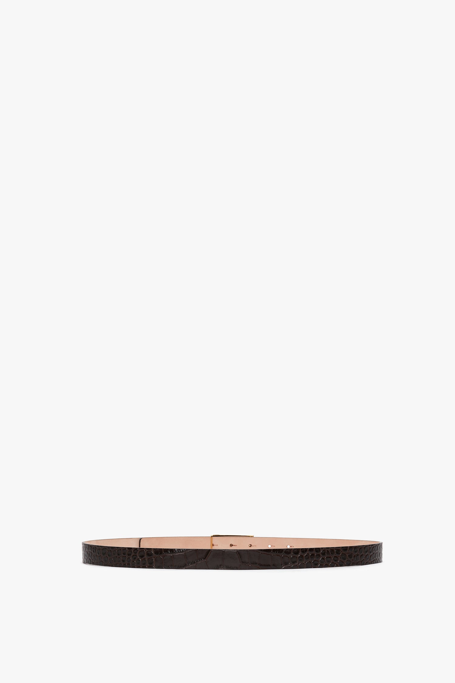 A thin black Frame Belt In Espresso Croc Embossed Calf Leather by Victoria Beckham, crafted from croc-embossed calf leather with a textured pattern and adorned with gold hardware in the form of a rectangular buckle, displayed against a white background.