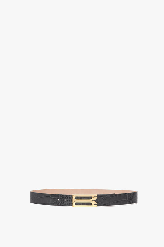 A Victoria Beckham Jumbo Frame Belt In Slate Grey Croc Embossed Calf Leather, featuring a crisscross pattern and a rectangular gold buckle, displayed on a white background.