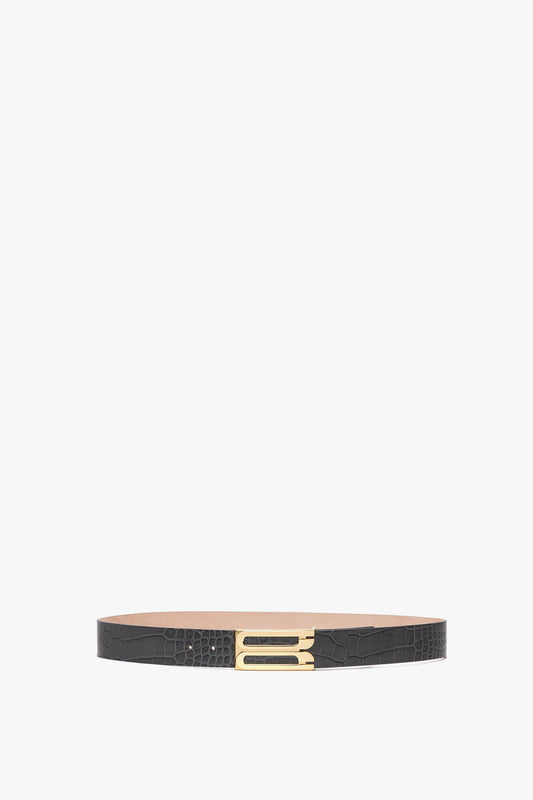 A thin Jumbo Frame Belt In Slate Grey Croc Embossed Calf Leather by Victoria Beckham in croc-embossed calf leather with a textured design and a small gold rectangular buckle, displayed on a white background.