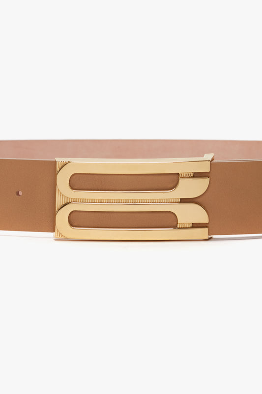 A contemporary belt made of smooth calf leather, this brown accessory features a gold rectangular buckle with a double-bar design. The *Jumbo Frame Belt In Camel Leather* by *Victoria Beckham*.
