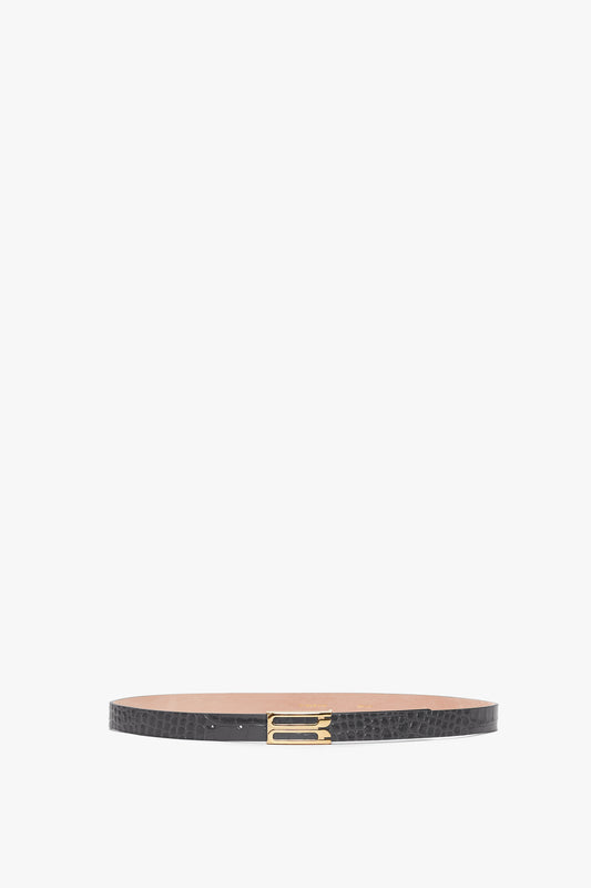A slate grey croc-embossed calf leather Frame Belt In Slate Grey Croc Embossed Calf Leather with gold hardware, displayed in a horizontal position against a white background by Victoria Beckham.