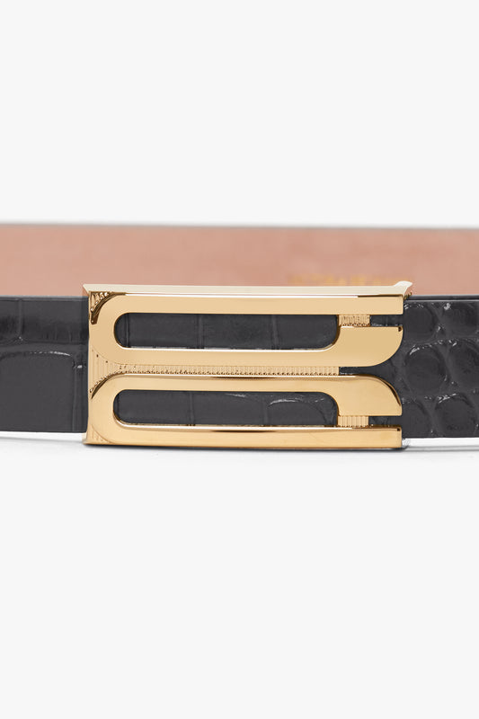 Close-up of a black croc-embossed calf leather Frame Belt In Slate Grey Croc Embossed Calf Leather by Victoria Beckham with gold hardware featuring a modern, geometric design.