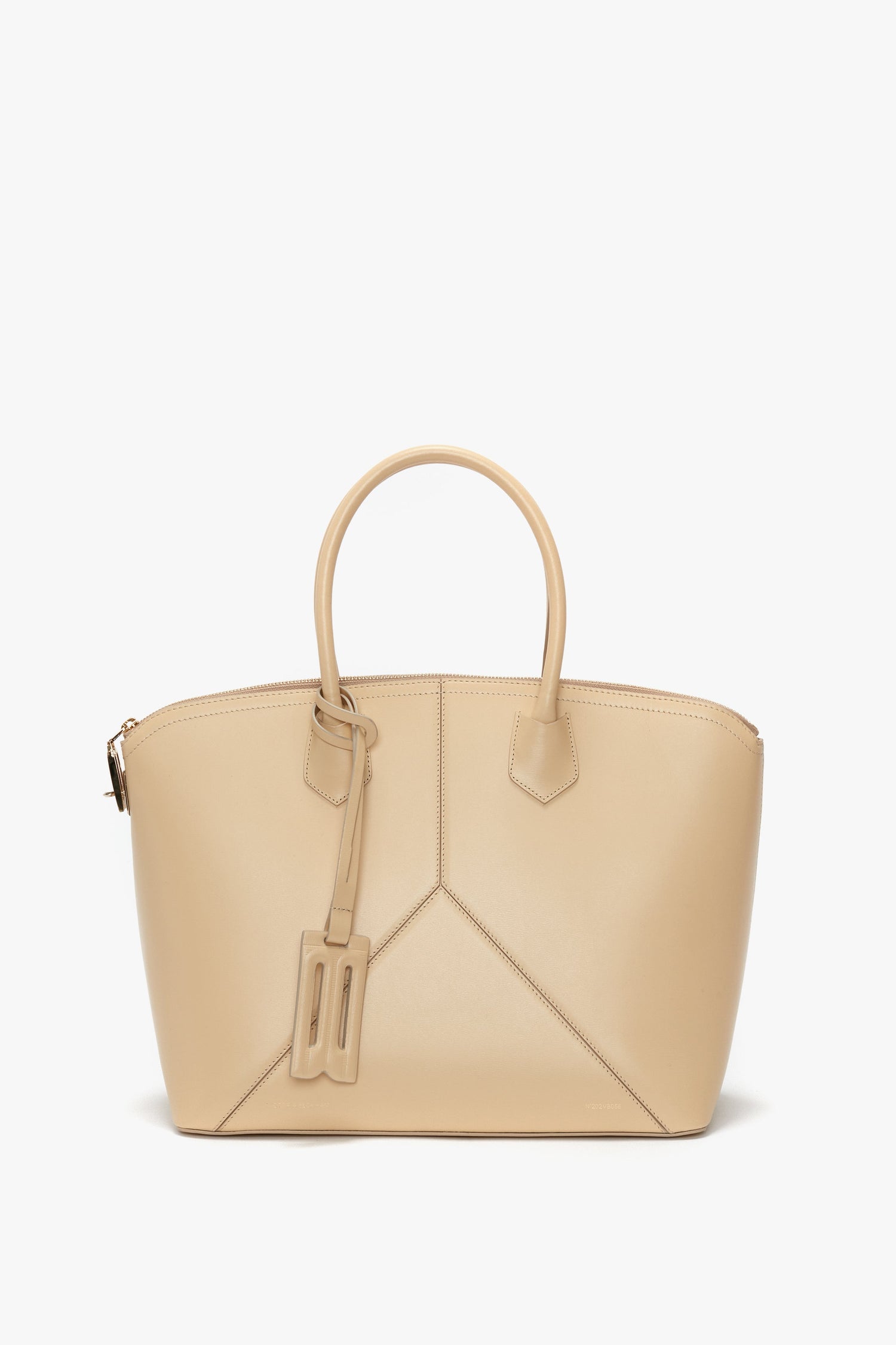 Victoria Beckham Victoria Bag In Sesame Leather: Beige leather handbag with dual handles and minimalist stitching, featuring a small attached tag and sleek leather panels.