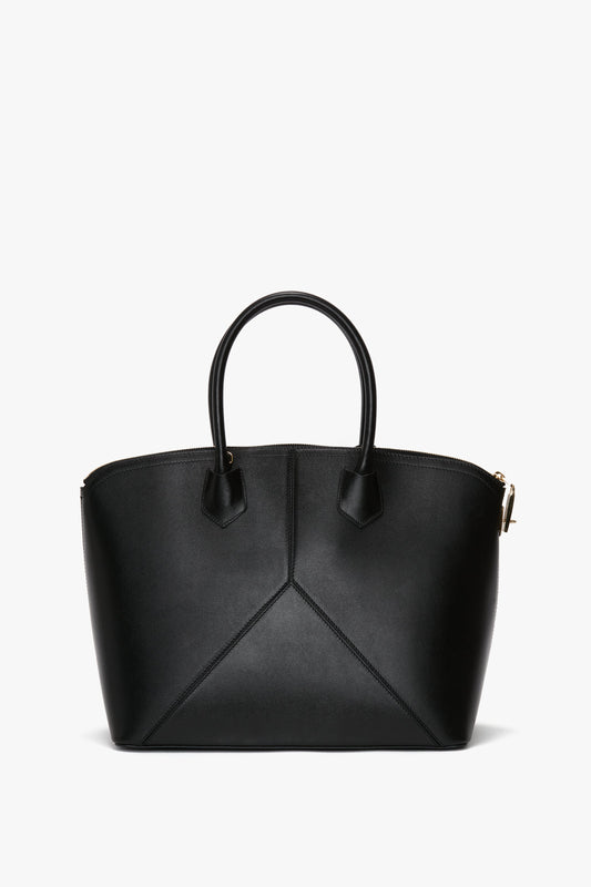 A Victoria Beckham Victoria Bag In Black Leather with two short handles, a structured design featuring sleek leather panels, and gold-tone hardware, set against a plain white background.