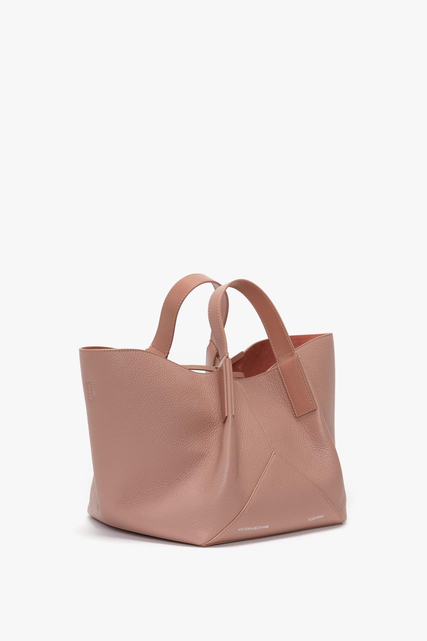 A large, structured pink leather tote bag with dual handles and an open top; introducing the Victoria Beckham W11 Mini Tote Bag In Marshmallow Leather.