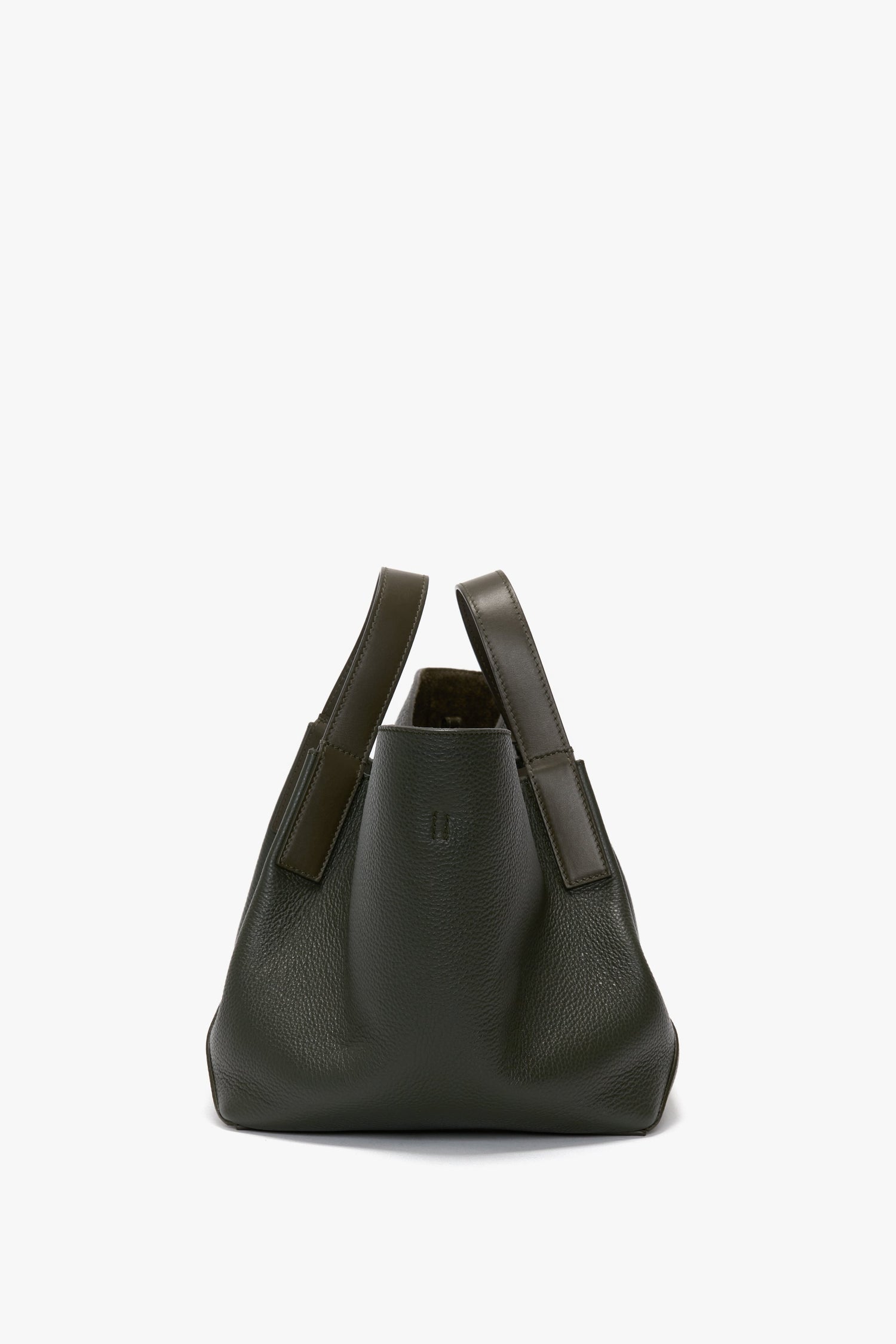 A W11 Mini Tote Bag In Loden Leather by Victoria Beckham with a soft, rounded shape and two short handles, crafted from luxurious suede, stands against a plain white background.