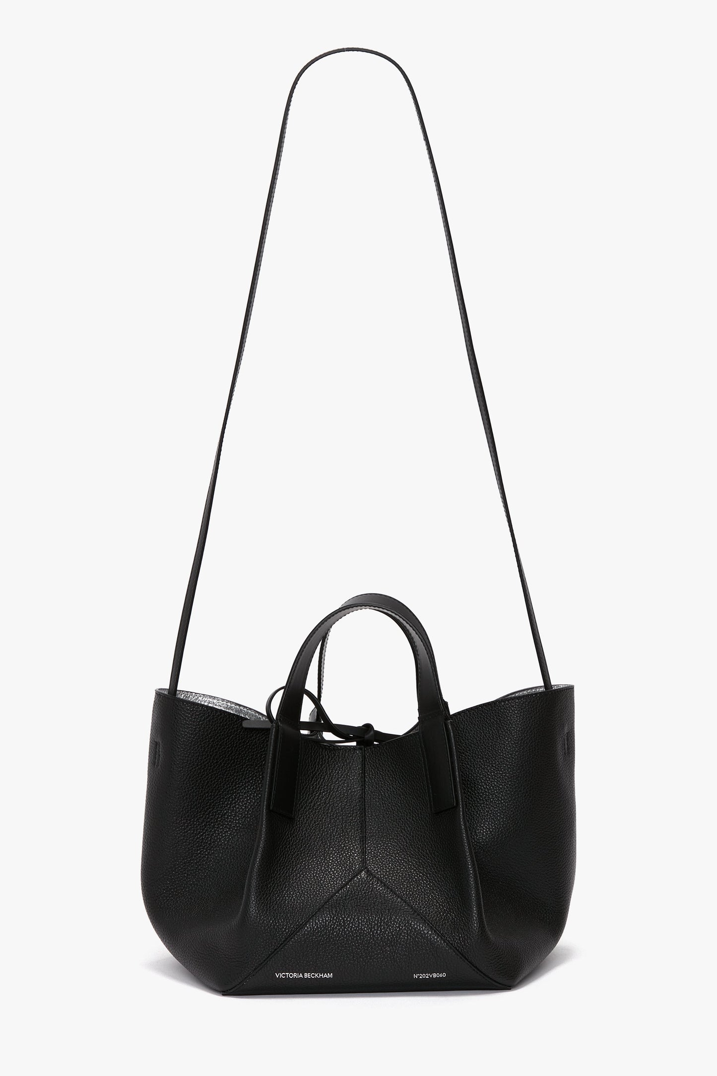A black leather W11 Mini Tote Bag In Black Leather from Victoria Beckham with rounded edges, two short handles, and a long shoulder strap crafted from grainy calf leather, displayed against a white background.