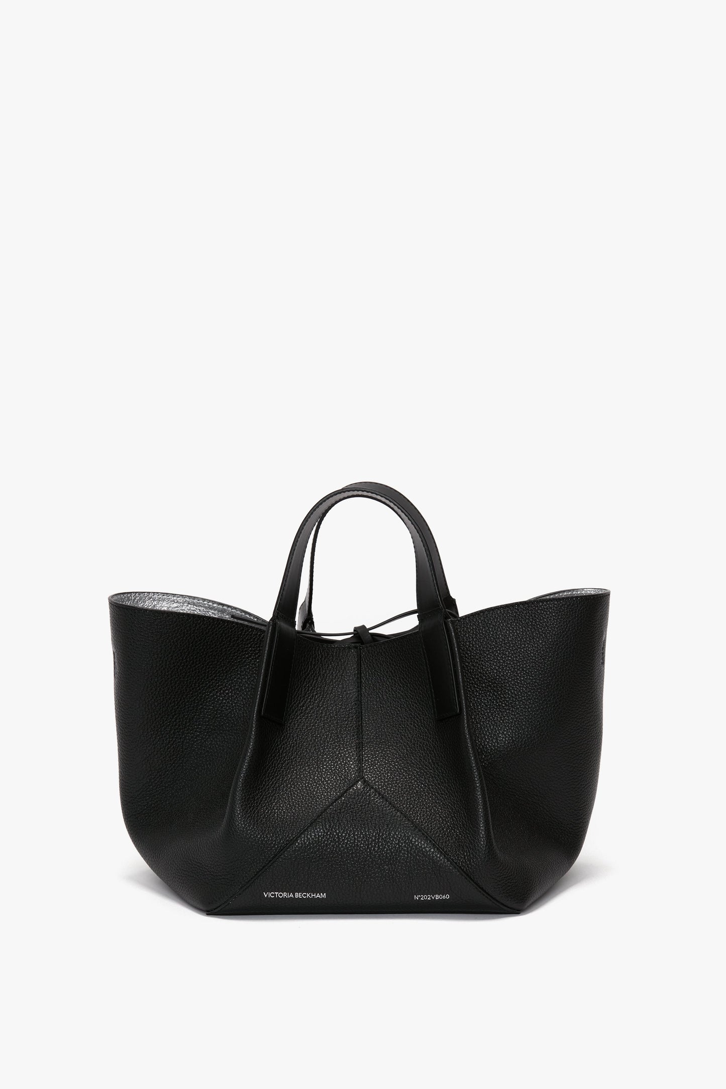 A W11 Mini Tote Bag In Black Leather by Victoria Beckham with short handles, crafted from grainy calf leather, featuring a structured design and minimal branding at the bottom.