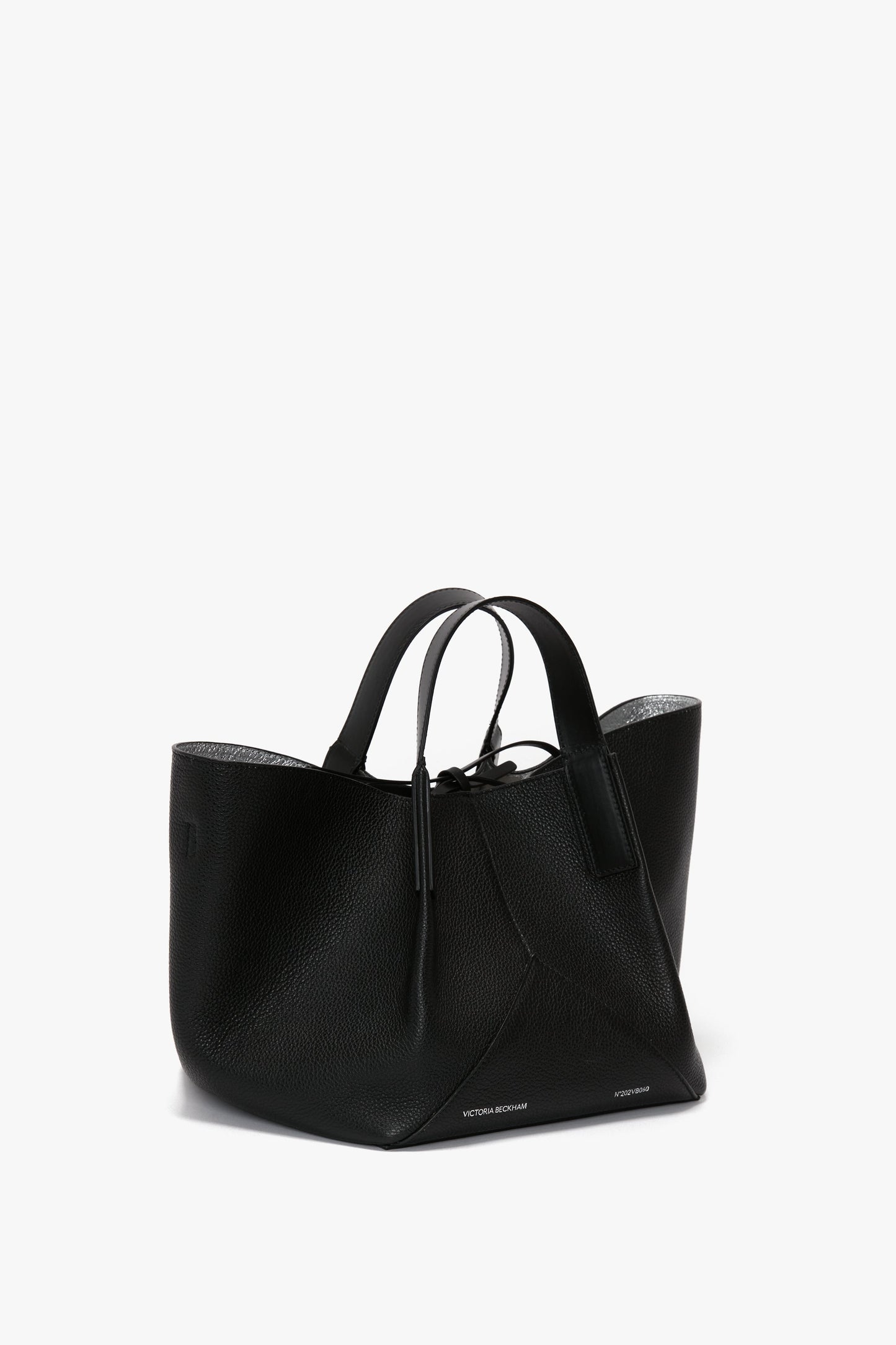 The W11 Mini Tote Bag In Black Leather by Victoria Beckham has two top handles, crafted from grainy calf leather for a touch of luxurious sophistication and minimalist design.