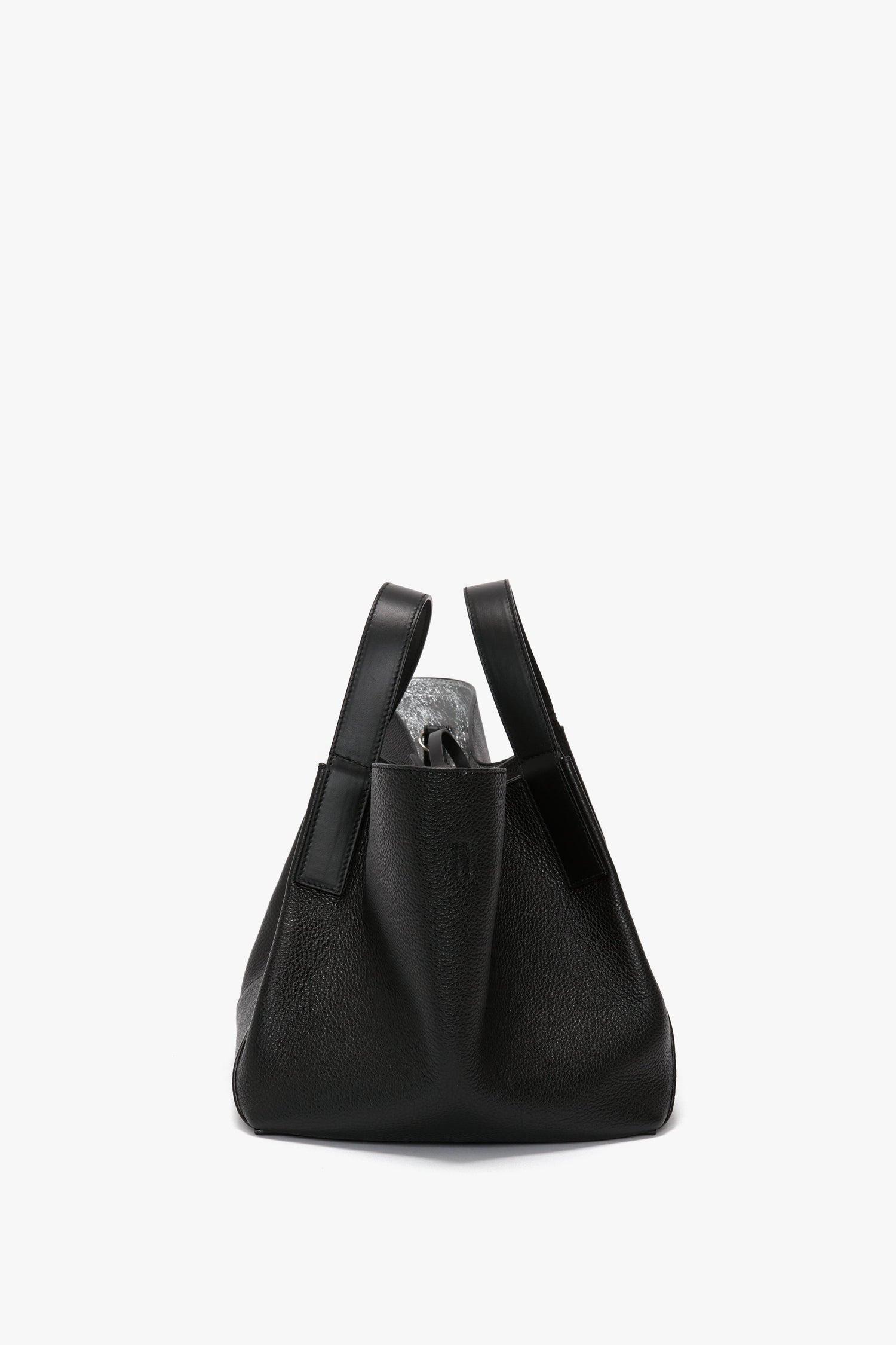 The Victoria Beckham W11 Mini Tote Bag In Black Leather, made from grainy calf leather, featuring a wide, slouchy design and two handles, photographed against a plain white background.