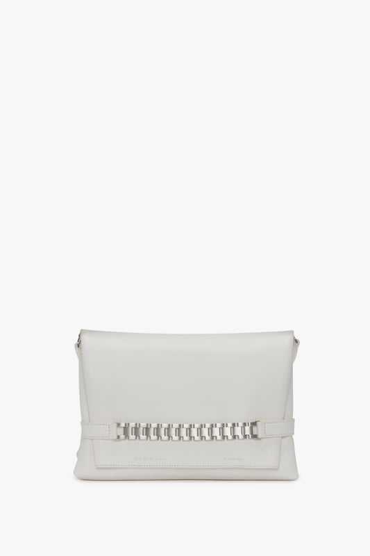A white leather Chain Pouch with Brushed Silver Chain In White by Victoria Beckham, with a rectangular shape, silver chain embellishment in the middle, and a top flap closure. It features foil-embossed branding and comes with a detachable strap for versatile styling.