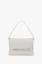 A Chain Pouch with Brushed Silver Chain In White by Victoria Beckham with a single top handle, a decorative woven pattern on the front, and foil-embossed branding.