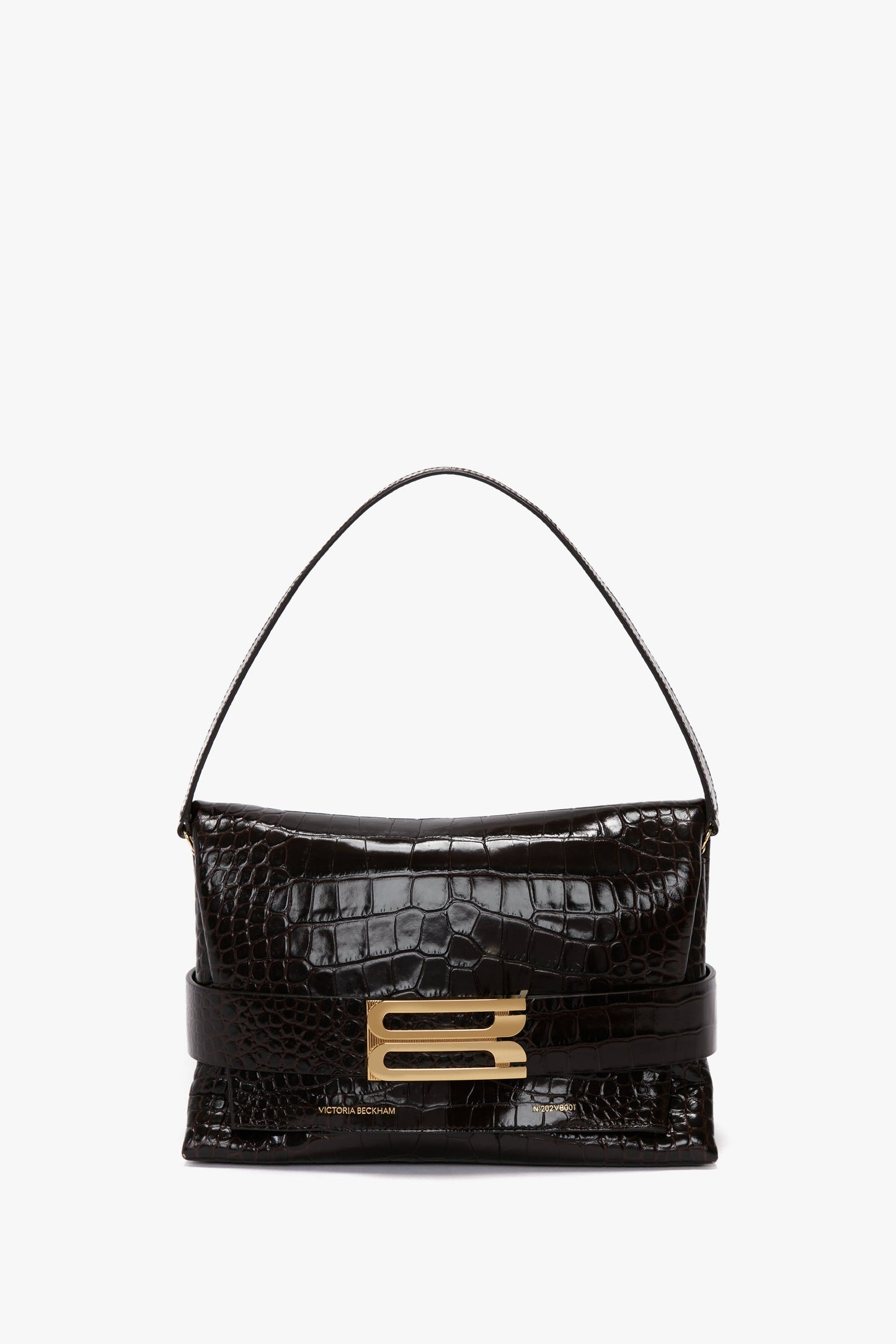 A black, textured leather B Pouch Bag In Croc Effect Espresso Leather by Victoria Beckham features a short handle and a prominent gold 'B' logo on the front clasp.