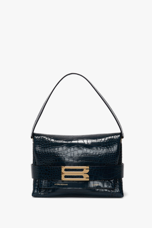 A Victoria Beckham B Pouch Bag In Croc Effect Midnight Blue Leather with a short handle and gold hardware embellishment on the front flap.