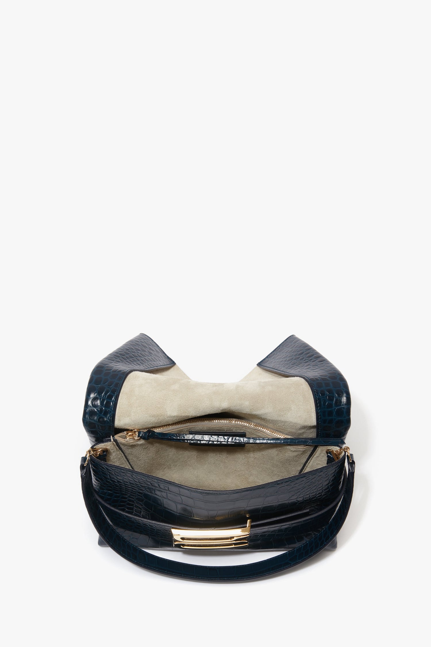 A B Pouch Bag In Croc Effect Midnight Blue Leather by Victoria Beckham is open, revealing a beige interior with a central zipped compartment and additional pockets.