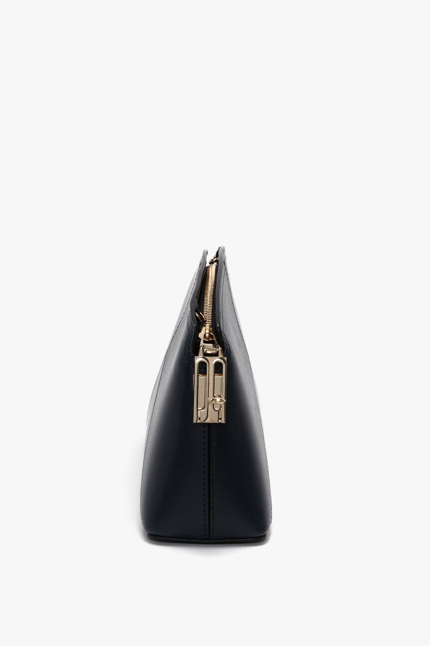 Side view of a chic Exclusive Victoria Crossbody Bag in navy leather with a gold zipper and stunning gold hardware, perfectly showcasing Victoria Beckham's elegant leather goods on a crisp white background.