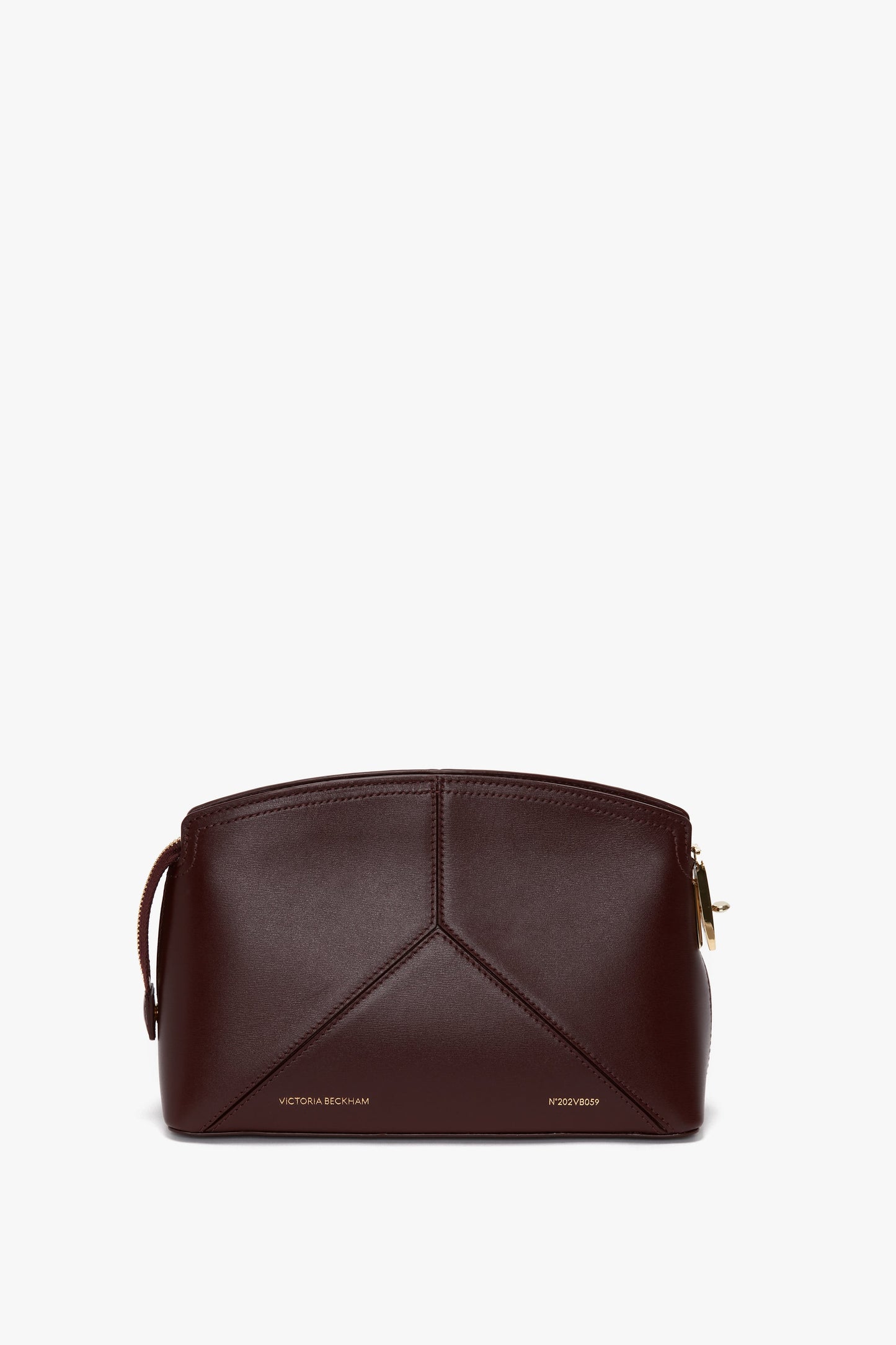 A Victoria Beckham Victoria Crossbody Bag In Burgundy Leather with a gold zipper and geometric stitching, crafted from textured calf leather. The front displays embossed gold lettering.