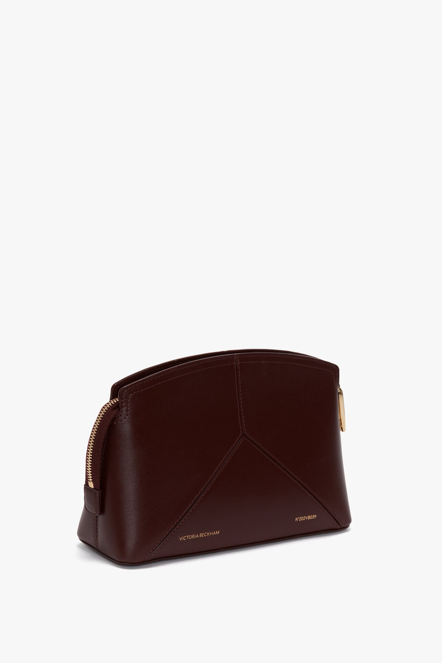 A Victoria Crossbody Bag In Burgundy Leather with gold zipper accents, displaying the brand names "Victoria Beckham" in gold lettering on the front side. The design is complemented by a secure padlock closure for added elegance.