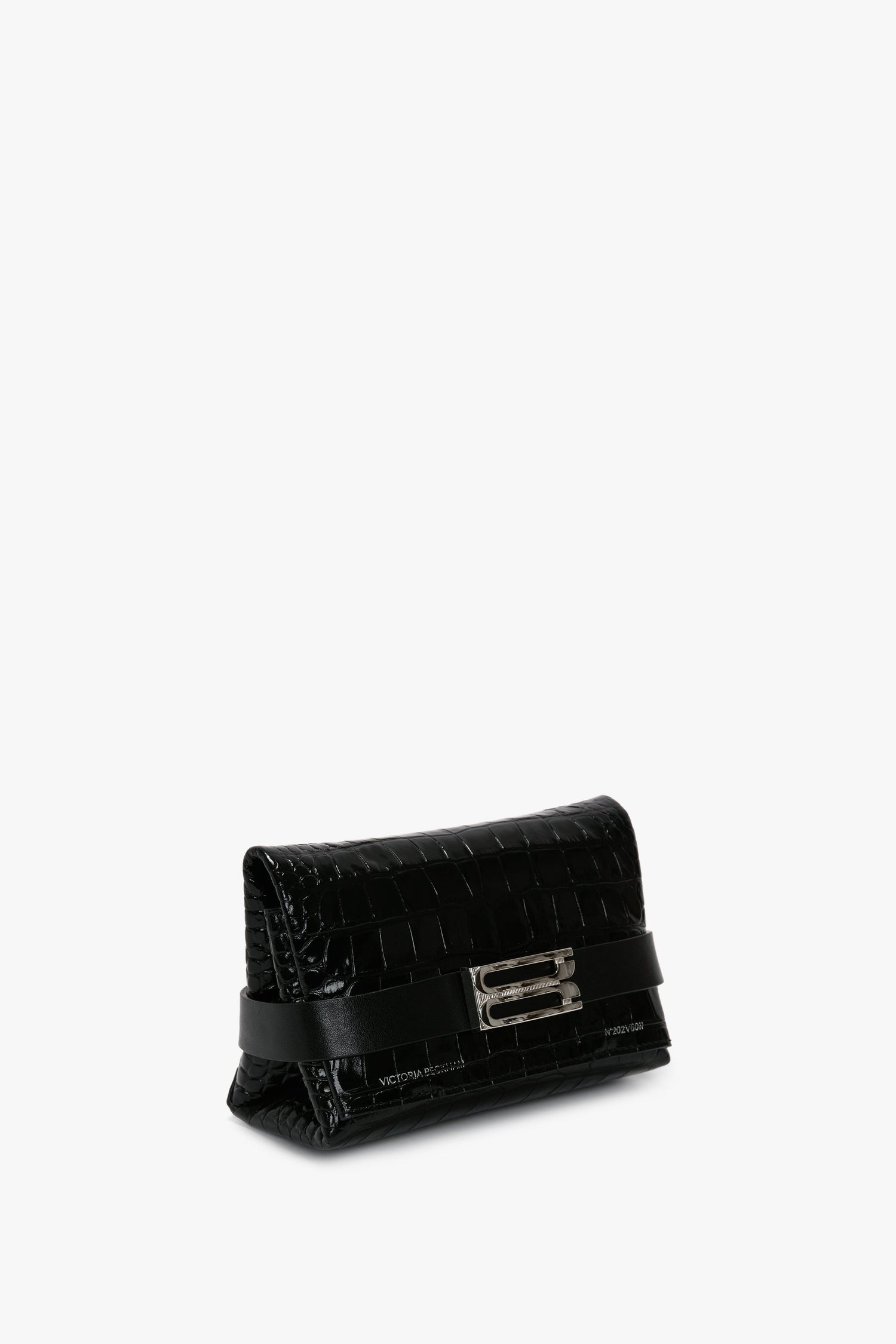 The Mini B Pouch Bag In Croc Effect Black Leather by Victoria Beckham, crafted from calf leather with a sophisticated crocodile pattern, features a silver buckle detail on the front and a detachable crossbody strap.