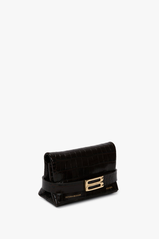 A Mini B Pouch In Croc Effect Espresso Leather by Victoria Beckham, featuring a subtle logo near the bottom edge and a detachable crossbody strap.