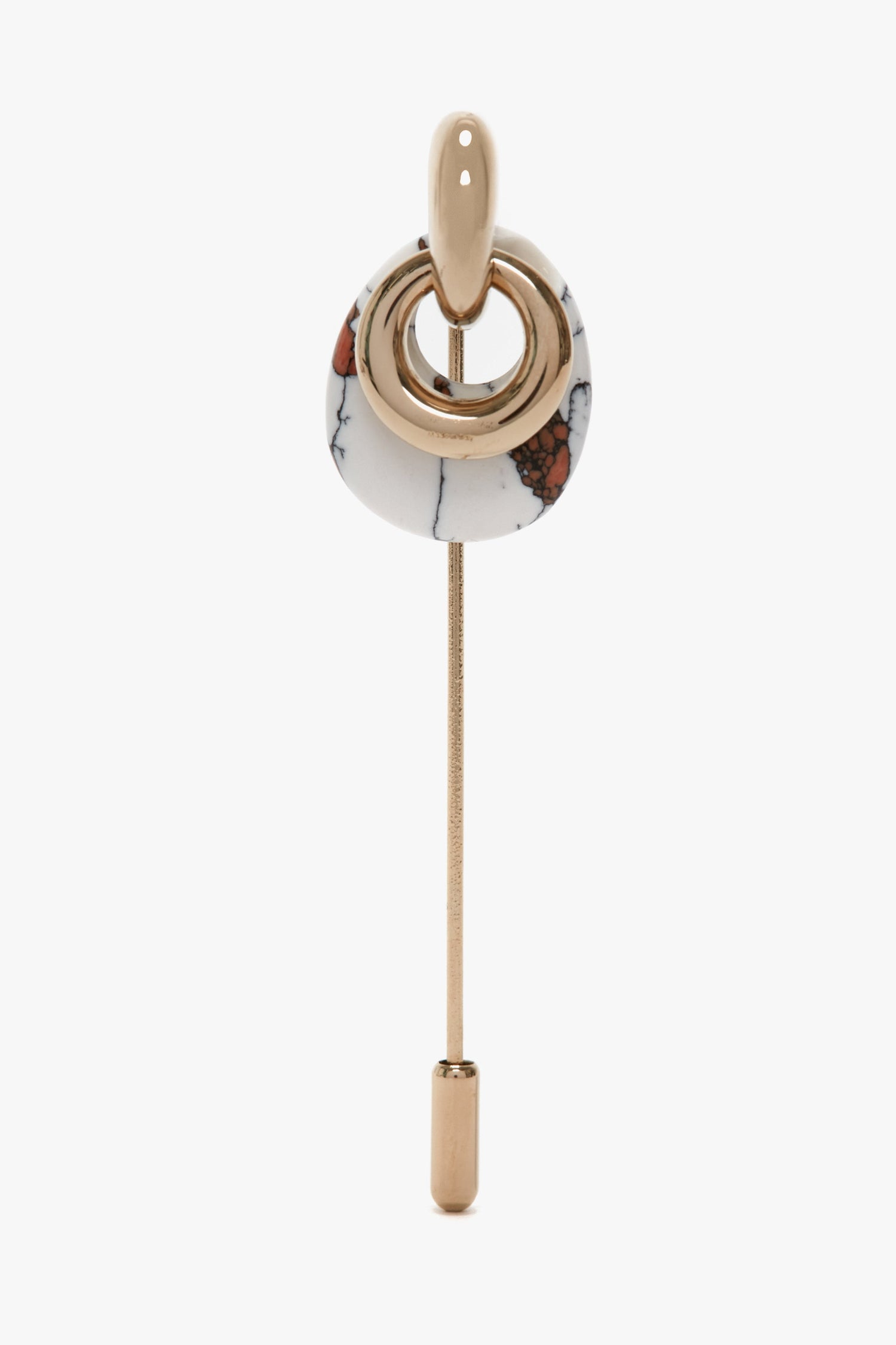 A decorative pin, made in Italy, featuring a light gold rod with an abstract circular design combining gold and marble-like elements at the top. This exquisite Victoria Beckham Exclusive Resin Charm Brooch In Light Gold-White boasts a Light Gold/White design that adds elegance to any outfit.