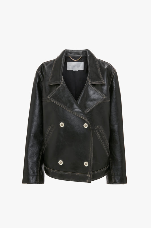 An Oversized Leather Jacket In Black by Victoria Beckham, made from black calf leather with wide lapels and silver buttons, featuring a subtle distressed finish, isolated on a white background.