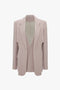 A light beige, classic tailored Victoria Beckham Double Panel Front Jacket In Rose Quartz with structured shoulders and lapels, featuring pocket detailing and an open front, displayed against a white background.