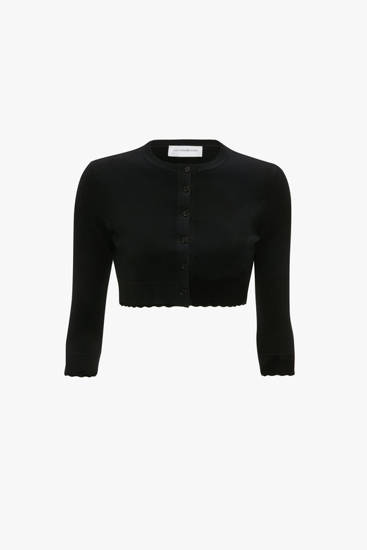 A black, long-sleeve VB Body Cropped Cardigan In Black by Victoria Beckham with buttons down the front, textured edges, and a form-fitting silhouette that exudes feminine sensibility.