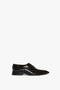 Victoria Beckham Pointy Toe Flat Lace Up in Black Brushed Leather with a low heel, four eyelets for laces, and a polished finish on a plain white background. These stylish lace-up shoes offer both elegance and comfort.