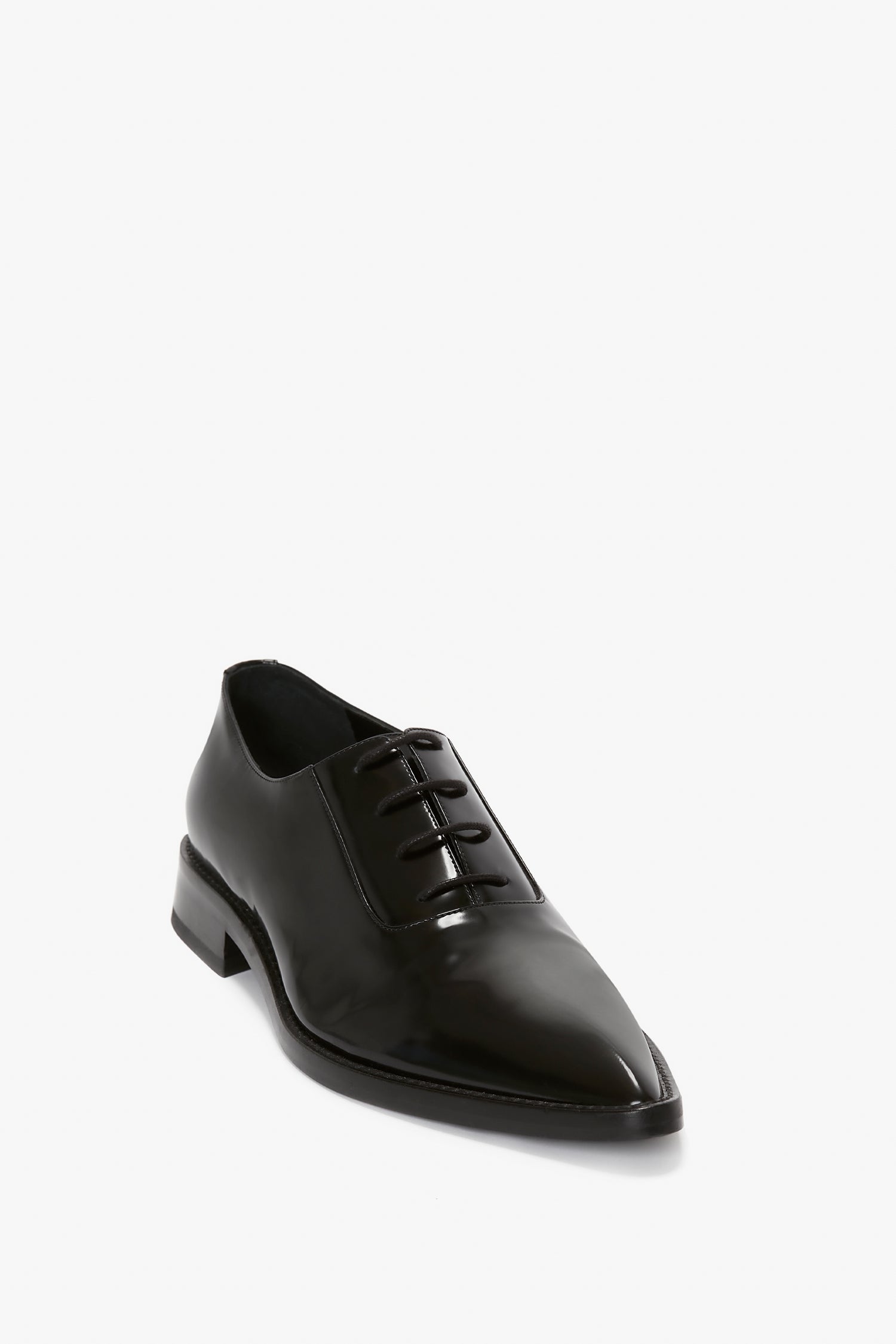 A single black brushed leather dress shoe with laces, featuring a pointed toe and low heel, is displayed against a plain white background. This Pointy Toe Flat Lace Up In Black Brushed Leather by Victoria Beckham seamlessly combines elegance with contemporary style.