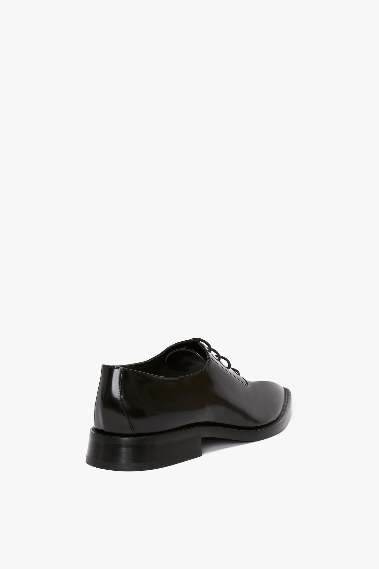 Victoria Beckham's Pointy Toe Flat Lace Up In Black Brushed Leather, designed in an Oxford brogue style, are shown from a rear three-quarter angle on a plain white background.